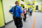 Ein Grenzwächter begleitete am Montag Migranten zur Personenkontrolle am Zoll des Bahnhofs Chiasso. (Bild: Keystone/Sara Solca)