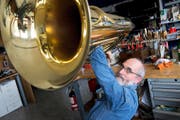Fritz Müller in seinem Blasinstrumenten-Atelier an der Obergrundstrasse 44 mit einer Bass-Tuba, die er gerade mit einem kleinen Hammer ausbeult. (Bild Dominik Wunderli)