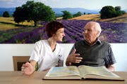 Walter Gerber wohnt auf der Pflegeabteilung im neuen Zentrum Pilatusblick in Ebikon. Hier berichtet er Pflegefachfrau Sibylle Kräuchi mit einem Atlas von früher. (Bild: Nadia Schärli / Neue LZ)