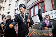 Zunftmeister Turi Müller (Mitte) und Zunftgotte Tildi Solèr (rechts) beim traditionellen Orangenauswerfen. (Bild: Philipp Schmidli)