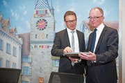 Michael Iten, der Präsident des Zuger Verbands der Raiffeisenbanken (links), und Matthias Brunner, der Vorsitzende der Bankleitung, besprechen sich am Geschäftssitz in Zug vor einem Gemälde des Zytturms. (Bild: Maria Schmid (Zug, 26. Januar 2018))