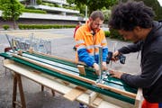 Benedikt Bucher, Leiter ReFit vom Strasseninspektorat Luzern, montiert zusammen mit einem Mitarbeiter eine Sitzbank. (Bild: Emanuel Ammon/pd)
