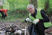 Der typische Fund am typischen Ort: Fridolin Andermatt steckt in seinen Güselsack einen Plastikbecher, den er bei einer Feuerstelle am Hüribach in Unterägeri gefunden hat. (Bild: Charly Keiser (16. September))