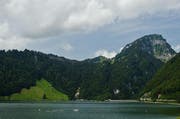 Ort des Unfalls, rechts der Gross Aubrig, an dessen Bergflanke die Alpgebäude liegen. Der Wanderweg führt über die grosse Wiese beim Schrä (links) hinauf zur Alp Bärlaui. Oberhalb der Boote, in der Waldschneise, verlief die Unglücksbahn. (Bild: Erhard Gick / Neue SZ)