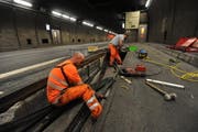 Zwei Mitarbeiter ziehen im Gotthard-Tunnel ein neues Kabel für das neue Videoüberwachungssystem ein. (Bild: Urs Hanhart)
