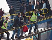 Grenzschutzbeamte begleiten einen Flüchtling auf eine Fähre. (Bild: Petros Giannokouris/AP (Lesbos, 8. April 2016))