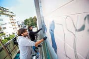 Christian Rebecchi (vorne) und Pablo Togni bemalen die Neubad-Fassade. (Bild: Roger Grütter)