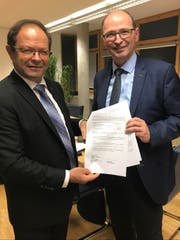 Regierungsrat Josef Hess (links) nimmt vom Direktor des Bundesamts für Umwelt, Marc Chardonnens, die Subventionsverfügung für das Projekt Hochwassersicherheit Sarneraatal, Teilprojekt Stollen Ost, in Höhe von 74,8 Millionen Franken entgegen. (Bild: PD)
