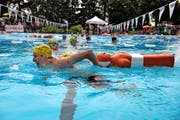 Ein jugendlicher Rettungsschwimmer von der SLRG Luzern zieht eine Puppe durch das Becken (oben). Fröstelnde Zuschauer beobachten einen Wettkämpfer beim Rettungsballwerfen. (Bilder Nadia Schärli)
