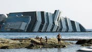 Touristen sonnen sich vor dem Wrack der «Costa Concordia». (Bild: Gregorio Borgia/AP (Giglio, 12. Juli 2012))