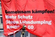 Trillerpfeifen, Fahnenmeer und Transparente gehören bei einer Demonstration dazu. Das Bild zeigt ein kletterndes Unia-Mitglied an einer Kundgebung von Bauarbeitern im vergangenen Juni in Zürich. (Bild: Keystone/Valeriano Di Domenico)