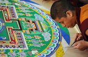 Der buddhistische Mönch formt aus Sand ein Mandala. (Symbolbild Keystone)