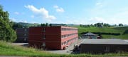 Die Holzmodul-Provisorien der Kantonsschule Menzingen: links die beiden 3-geschossigen Schulhaustrakte, vorne rechts der eingeschossige Mensabau mit Küche. (Bild: PD)