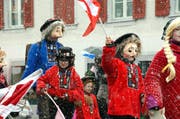Mit Fahnen und Alpenrosen durch das Schneegestöber: Brauchtum will gepflegt sein. (Bild: Adrian Venetz / Neue OZ)