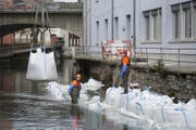 Die Bauarbeiter erstellen mit schweren Säcken eine Wasserhaltung. (Bild: Maria Schmid)