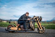 Kilian Vogel auf seinem selbst gebauten Holzmotorrad. Die Räder des Gefährts bestehen aus Bierfässern. (Bild Dominik Wunderli)