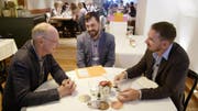 Diskutieren an einem Tisch an der wöchentlichen Sitzung bei Remimag: Peter Eltschinger (links) mit seinen Söhnen Bastian und Florian. (Bild: SRF)