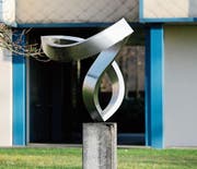 Die Stahlblechplastik «Zigi Zagi» von Josef Staub war 1983 eine Schenkung an die Stadt Zug. Das Kunstwerk ist auf einer Betonkonsole fixiert und steht auf der Wiese hinter dem Hertizentrum.