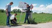 Daniel Schillig, Präsident des Vernetzungsprojekts, Landwirt Richard Zurbrügg und Dominik Iten, Präsident des Zuger Vogelschutzes (von links) montieren eine Infotafel bei der Zufahrtsstrasse zum Hof Frohbüel. (Bild: Maria Schmid (Menzingen, 3. Juli 2017))