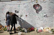 Zwei Mädchen schreiben Beileidsbekundungen auf eine Wand in der Nähe des zerstörten Hochhauses. (Bild: Alastair Grant/AP (15. Juni 2017, London))