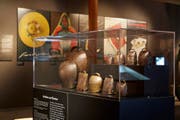 Die Ausstellung zeigt unter anderem eine Auswahl von Carigiets Plakaten. Im Vordergrund: Vitrine mit Schellen und Glocken aus dem Kanton Graubünden. (Bild: Mara Truog/Schweizerisches Nationalmuseum/Alois Carigiet Erben)