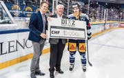 Der EVZ-Captain Raphael Diaz (rechts) und Florian Zimmermann (links) übergeben Josef Mathis von der Stiftung Eishockey-Nachwuchsförderung Innerschweiz einen Check über 1 (Bild: PD)