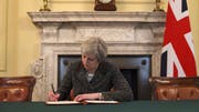 Auf einem offiziellen Foto ist zu sehen, wie die britische Premierministerin May den Brief an die EU unterzeichnet. (Bild: RTÉ News / Twitter)