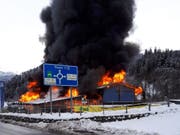 Meterhohe Flammen und eine dicke Rauchsäule: Das Landi-Gebäude in Thusis GR steht in Vollbrand. (Bild: Fabiana Calsolaro, sda)