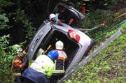 Das Auto kam in Schräglage zum Stillstand. Mitglieder der Feuerwehr Arth bergen den Fahrer aus dem Wagen. (Bild: Kantonspolizei Schwyz)