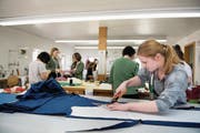 Seraina Waser (vorne rechts) schneidet im Atelier einen Stoff zu (Bild: Corinne Glanzmann (Stans, 14. März 2018))