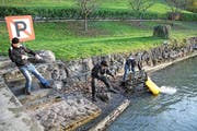 Helfer ziehen einen schweren Metallwagen aus dem Wasser. (Bild: PD)