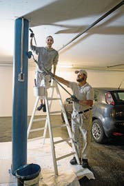 Walti von Büren von der Weidli-Werkstätte streicht zusammen mit Giulia Baudat von der Malerei Schmid AG eine Säule in einem Parkhaus des Bürgenstock-Resorts. (Bild: Corinne Glanzmann (Bürgenstock, 11. Juli 2017))