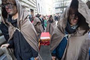 Eine Gruppe von Gewerbeschülern zieht ein selbst gefertigtes Buch hinter sich her. (Bild: Keystone / Sigi Tischler)