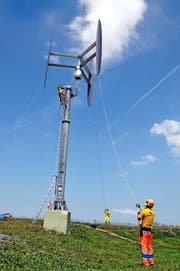 Präzisions- und Teamarbeit: Die Bodencrew platziert das Windrad, das noch am Helikopter hängt, auf dem Masten. (Bild Matthias Piazza)