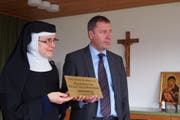Der Nidwaldner Regierungsrat Othmar Filliger überreicht der «Kräuterschwester» Maria Brigitta Graf die Messingtafel mit der Auszeichnung. (Bild: PD)