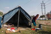 Eine Frau wäscht Ende November Kleider vor ihrem Zelt. Dieses befindet sich in einem Camp in Kathmandu, welches für die Überlebenden des Erdbebens im April erstellt wurde. (Bild: Keystone / Niranjan Shrestha)