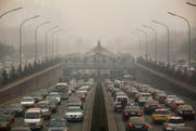Autos fahren unter der verschmutzten Luft von Peking den Strassen entlang. (Bild: Archiv / Keystone)