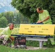 Die Werkdienstmitarbeiter Gody Durrer (links) und Daniel Michel montieren an der Zubenstrasse in St. Niklausen eine der zwanzig gelb- blauen Sitzbänke. (Bild: PD)