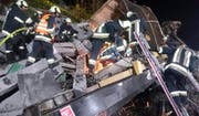 Feuerwehrleute setzen auf einem mit Bahnschwellen beladenen, zerstörten Wagen Schneidbrenner ein. (Bild: Keystone/APA/Freiwillige Feuerwehr Brixen)