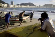 Fischer schieben an der Copacabana ihr Boot ins Meer. (Bild: AFP)