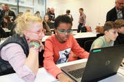 Sarner Oberstufenschüler spielen «Finance Mission Heroes». Gymnasiallehrerin Scarlett Dubois lässt sich das neue Spiel von Nael Kiefer erklären. Ebenfalls im Finanzspiel vertieft ist Adriatik Alija (rechts). Bild: Marion Wannemacher (Sarnen, 23. November 2016)