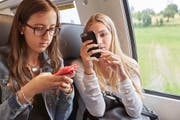 Zwei Frauen benutzen im Zug ihre Smartphones. (Bild: Keystone / Christof Schürpf)