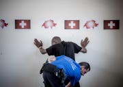 Ein Angehöriger des Grenzwachtkorps durchsucht am Zoll des Bahnhofs Chiasso einen Migranten. Laut gfs.bern setzt die SVP auf das Thema, das den Befragten am meisten unter den Nägeln brennt. (Bild: Keystone / Pablo Gianinazzi)