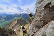 Arbeiter befestigen Armierungseisen am Felsen in luftiger Höhe über dem Gipfelrundweg. (Bild Christian Perret)