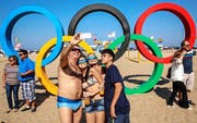 An der Copacabana läuft es wie immer rund: Diese Sonnenanbeter fotografieren sich vor den olympischen Ringen – ob sie auch wissen, was diese bedeuten? (Bild: Keystone/Sergei Ilnitsky)