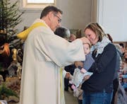 Pfarrer Thomas Meli segnet Leandra, gehalten von ihrer Mutter Antonia Enz. (Bild: Patricia Helfenstein-Burch (Alpnach, 28. Dezember 2017))