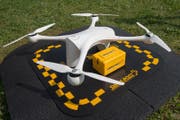 Eine Drohne wird mit einem Paket bestückt, das Laborproben enthält. (Bild: Pablo Gianinazzi / Keystone (Lugano, 31. März 2017))