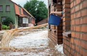 Wasserschöpfen aus der Haustür – Hochwasser nach sommerlichem Extremregen. (Bild: Silas Stein/dpa (Rhüden, 26. Juli 2017))