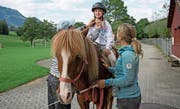 Die Therapeutinnen Rahel Bolliger und Flurina Schäli helfen Elin auf dem Islandpferd. (Bild: Corinne Glanzmann (Sachseln, 5. September 2017))