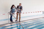 In einem symbolischen Akt giessen Schulpräsidentin Silvia Daucourt und Schulleiter Markus Abry gesegnetes Wasser ins neue Schwimmbecken. (Bild: Edi Ettlin (Oberdorf, 28. Oktober 2017))